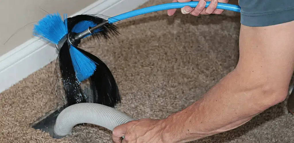 Dryer vent cleaning technician brushing lint from a vent line in Indianapolis, IN