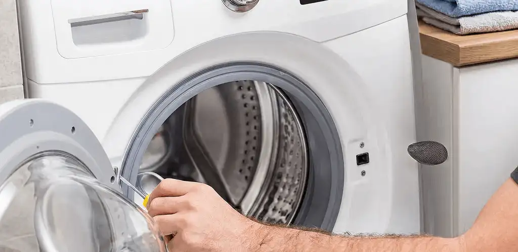 Handyman repairing a front-load washing machine and inspecting the drum in Indianapolis, IN