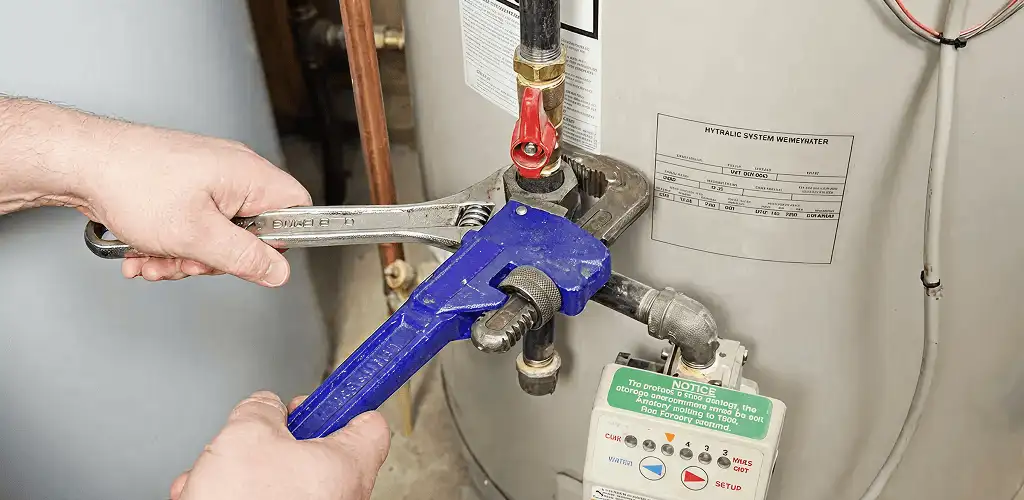 Water heater repair technician tightening the shutoff valve and supply line in Indianapolis, IN